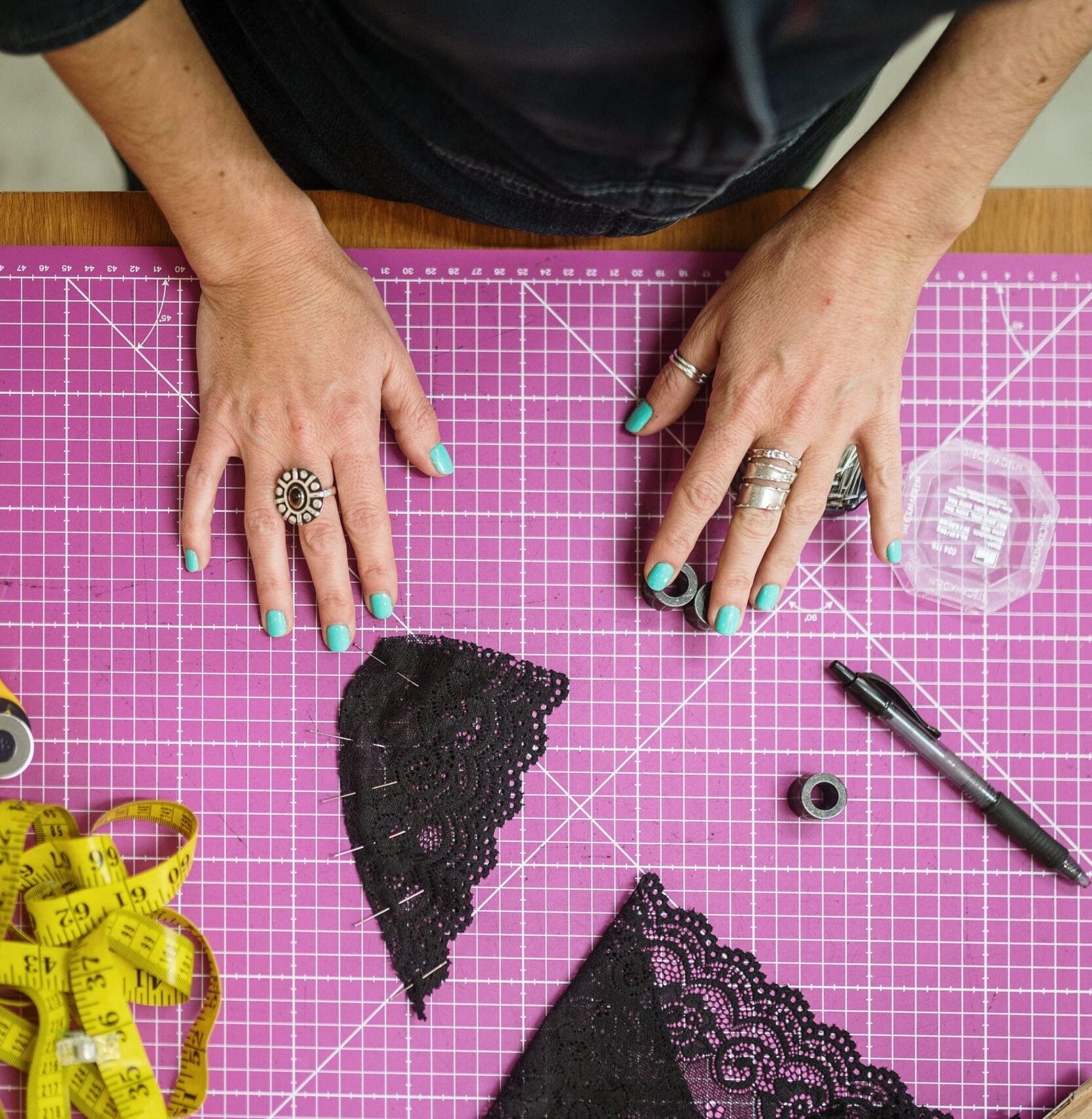 Tabla de corte con visión de manos de persona y patrones de encaje de bralette negros