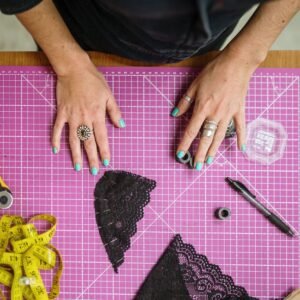 Tabla de corte con visión de manos de persona y patrones de encaje de bralette negros