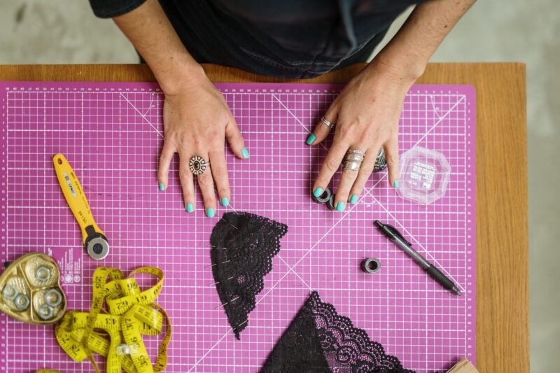 Tabla de corte con visión de manos de persona y patrones de encaje de bralette negros