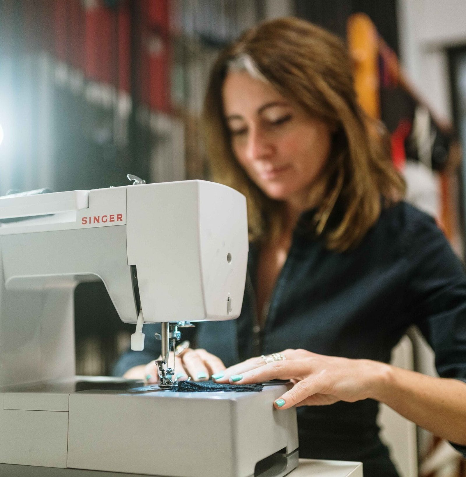 Mujer cosiendo en máquina de coser Singer girs