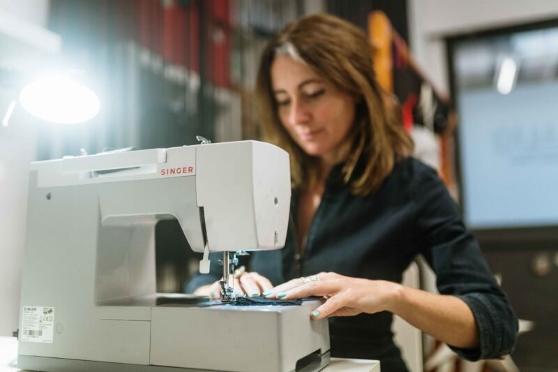 Mujer cosiendo en máquina de coser Singer girs