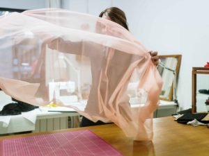 Mujer extendiendo tela rosada sobre una mesa