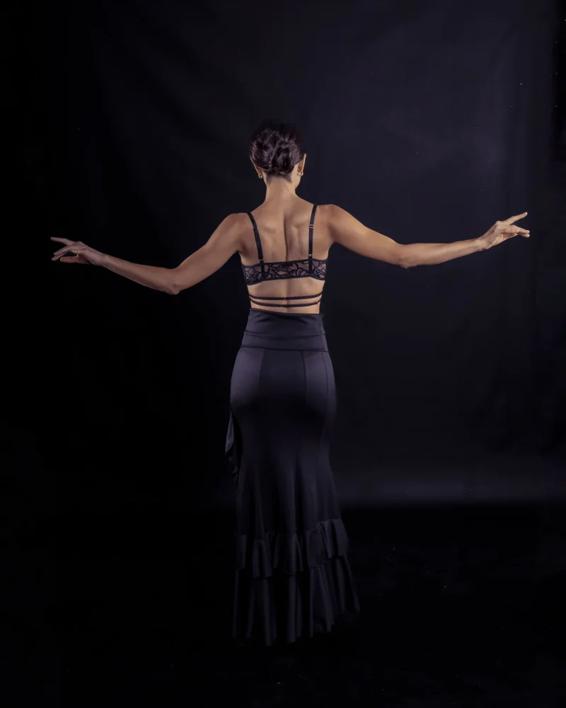 Mujer bailando flamenco en sujetador de encaje y falda negra